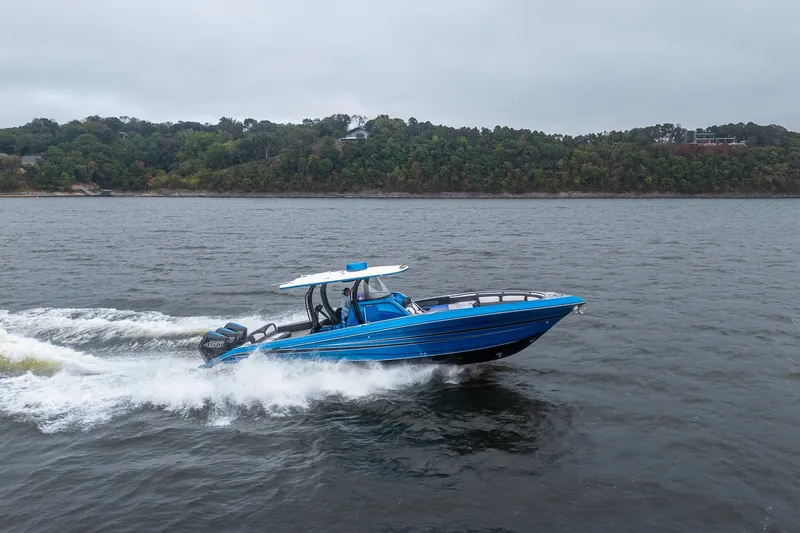 The Image of 2022 Fountain 39 NX boat cruising on a lake with forested shoreline. - 3