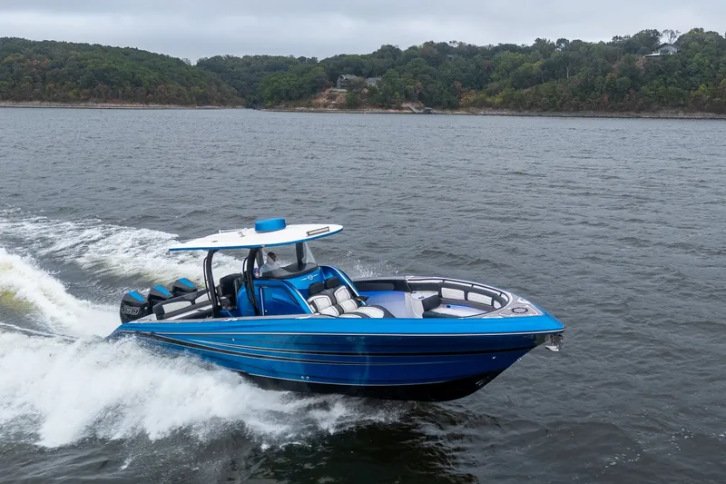 Slide: The Image of 2022 Fountain 39 NX boat cruising on a lake with lush green shoreline. - 2