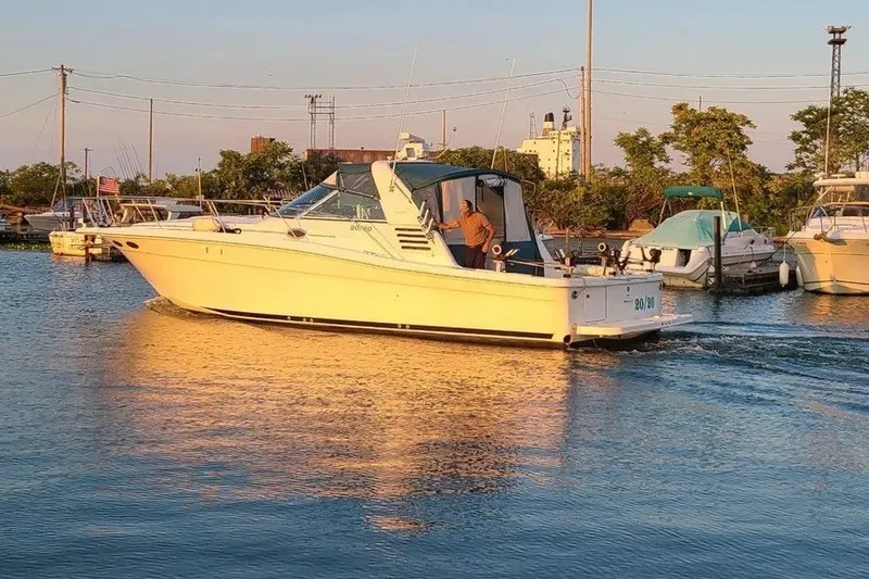 Slide: The Image of 1998 Sea Ray 370 Express Cruiser on calm water at sunset, docked near other boats. - 2