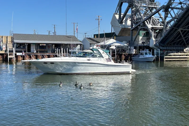 Slide: The Image of 1998 Sea Ray 370 Express Cruiser on calm water near a dock and bridge. - 4