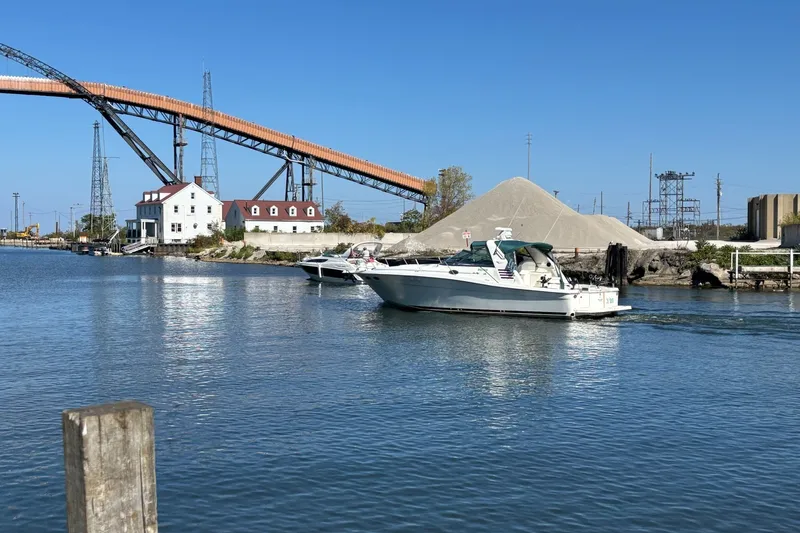The Image of 1998 Sea Ray 370 Express Cruiser on a calm river near industrial structures. - 1