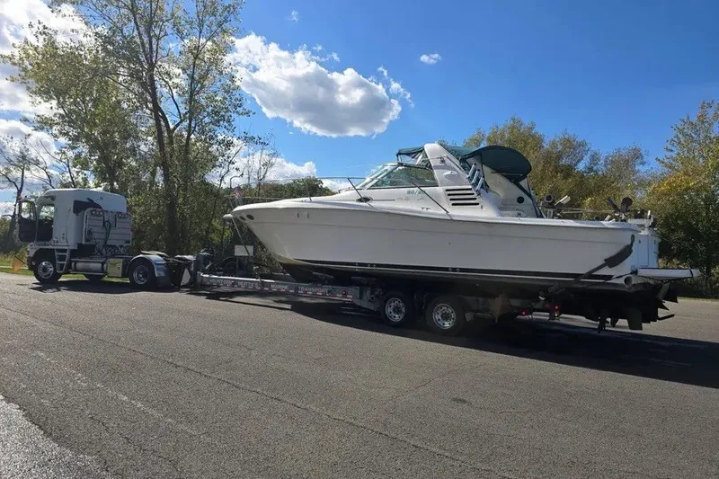 Slide: The Image of 1998 Sea Ray 370 Express Cruiser on trailer, transported by truck under clear blue sky. - 13