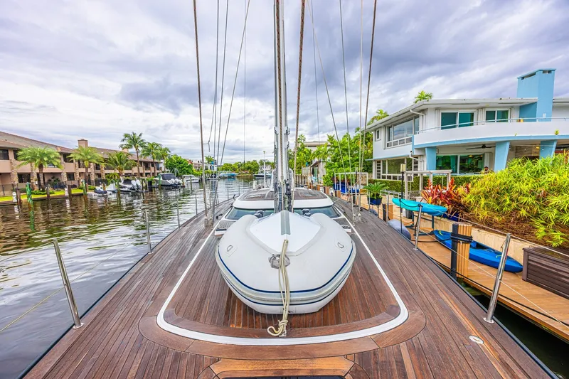 Slide: The Image of Luxurious CNB 70 yacht docked by waterfront homes, showcasing sleek wooden deck, 2007 model. - 24