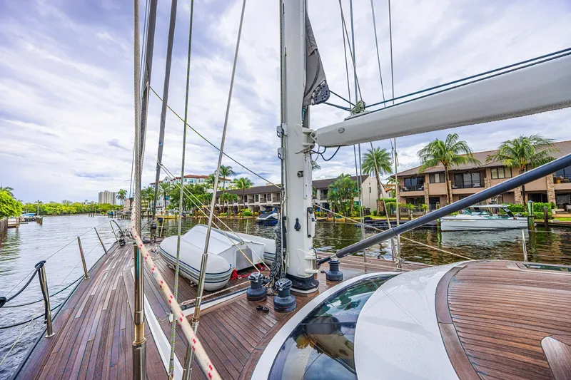 Slide: The Image of Luxurious 2007 CNB 70 yacht docked near waterfront homes, showcasing sleek wooden deck. - 25