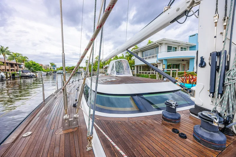 Slide: The Image of Luxurious 2007 CNB 70 yacht docked by waterfront homes, showcasing sleek wooden deck. - 22
