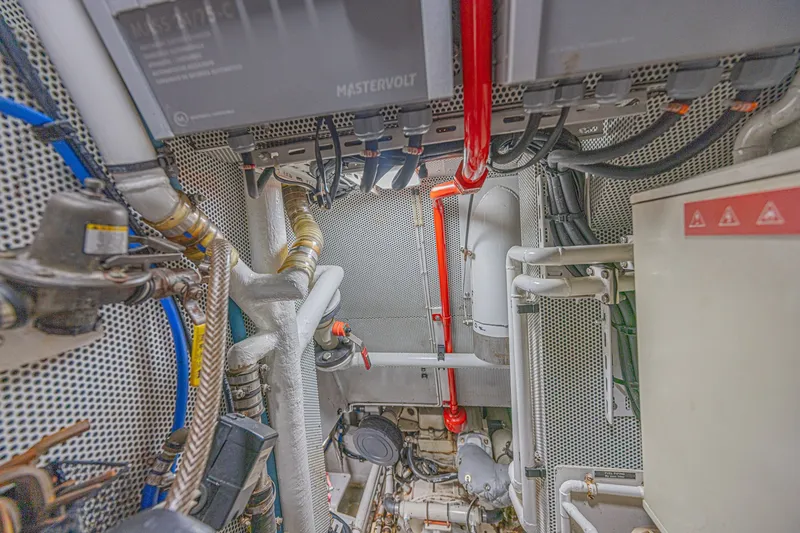 Slide: The Image of Engine room of a 2007 CNB 70 yacht, featuring complex piping and wiring systems. - 61