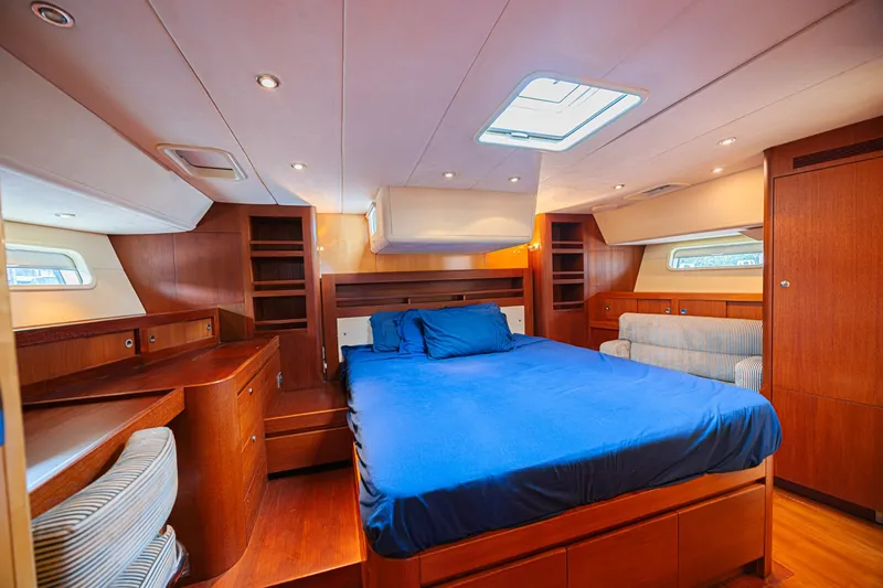 Slide: The Image of Luxurious CNB 70 yacht bedroom, 2007 model, featuring elegant wood finishes and blue bedding. - 48