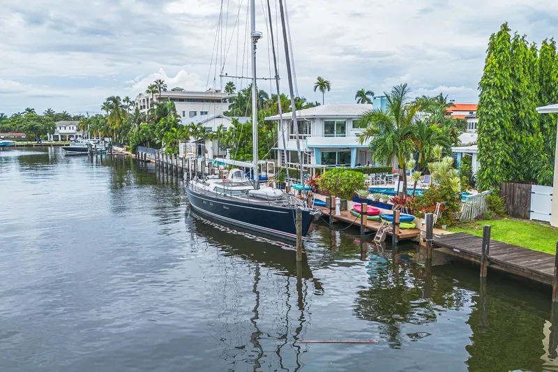 Slide: The Image of Sailboat docked by waterfront homes, CNB 70 model, 2007, lush greenery, calm waterway. - 14