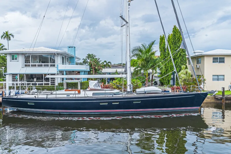 The Image of Luxurious 2007 CNB 70 yacht docked by waterfront homes, surrounded by lush greenery. - 3
