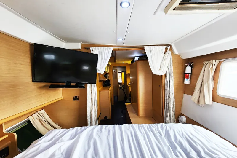 Slide: The Image of Interior of a 2008 Lagoon 500 yacht cabin with TV, bed, and wooden decor. - 45