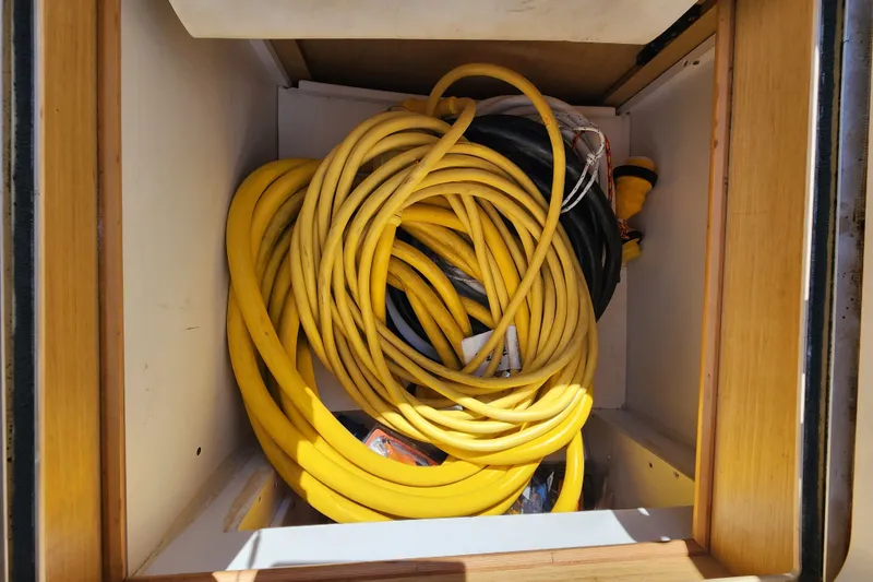 Slide: The Image of Coiled yellow hose stored in a compartment of a 2008 Lagoon 500. - 71