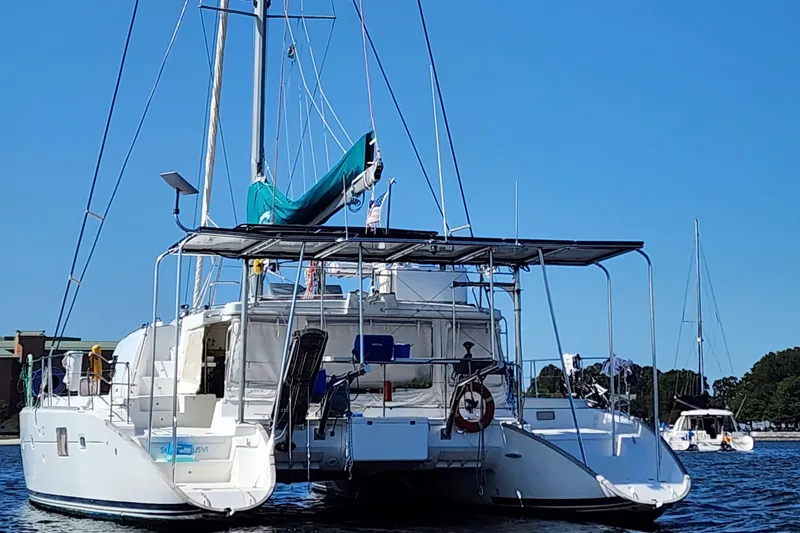 Slide: The Image of 2008 Lagoon 500 catamaran on water, featuring solar panels and a blue sail under clear skies. - 22
