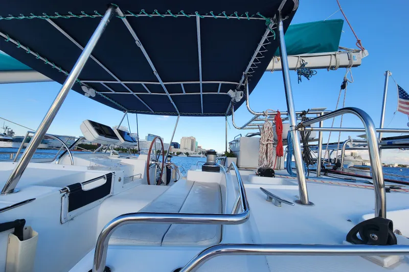 Slide: The Image of 2008 Lagoon 500 yacht deck with blue canopy, docked in a marina, city skyline in background. - 16