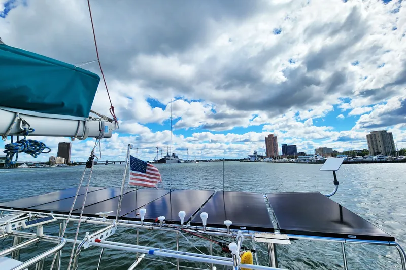 Slide: The Image of Sailing on a 2008 Lagoon 500 catamaran with solar panels, American flag, and city skyline. - 21