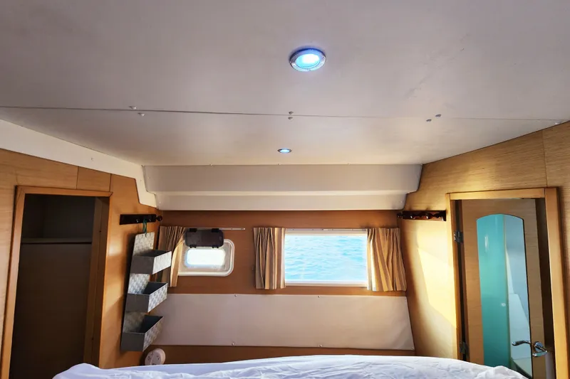 Slide: The Image of Interior cabin of 2008 Lagoon 500 yacht with window, bed, and wooden finish. - 59