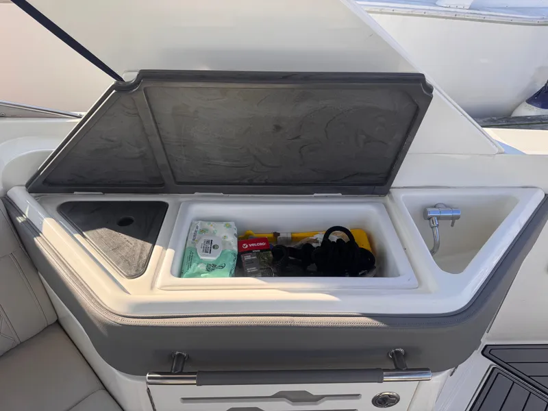 Slide: The Image of An open storage compartment on a Sea Ray SLX 310 Outboard boat reveals cleaning supplies and accessories. - 12