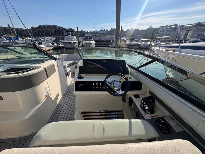 Slide: The Image of The image shows the cockpit of a 2020 Sea Ray SLX 310 Outboard. It is docked in a marina. - 15