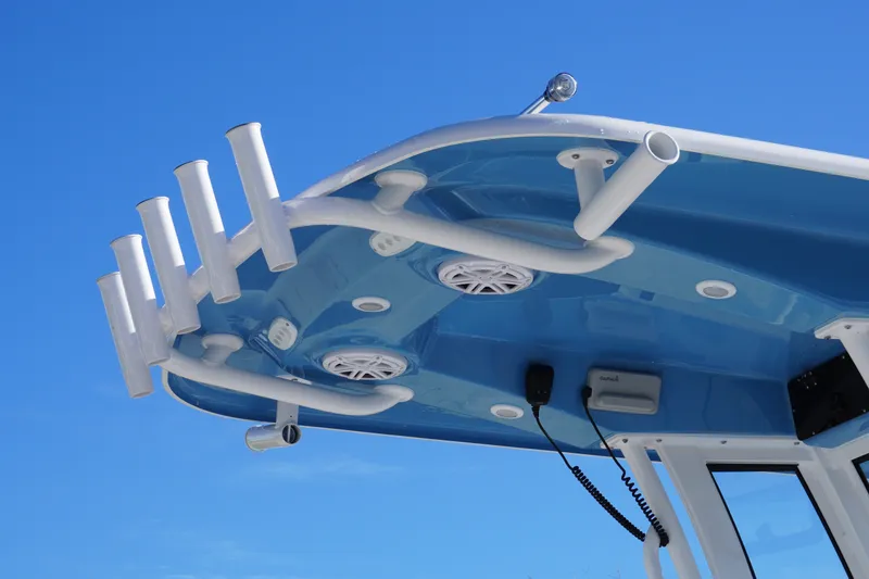 Slide: The Image of 2026 Sportsman Heritage 231 Center Console boat with rod holders and speakers against blue sky. - 9