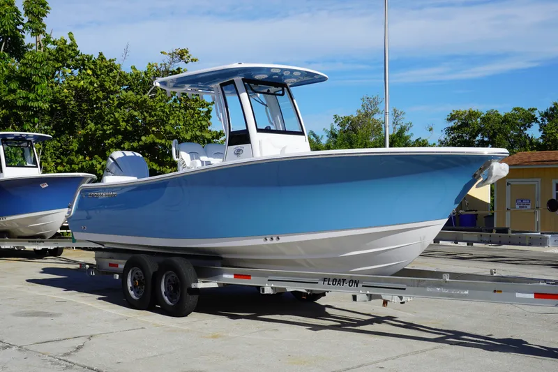 The Image of 2026 Sportsman Heritage 231 Center Console boat on trailer, blue hull, outdoor setting. - 0