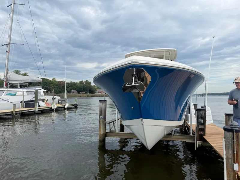 Slide: The Image of A blue and white 2014 Sailfish 290 CC is docked. The sky is cloudy. - 2