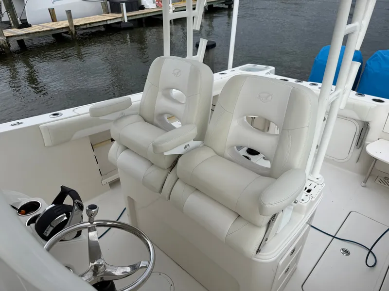 Slide: The Image of Two cushioned captain's chairs on a boat with a steering wheel and water in the background. - 21
