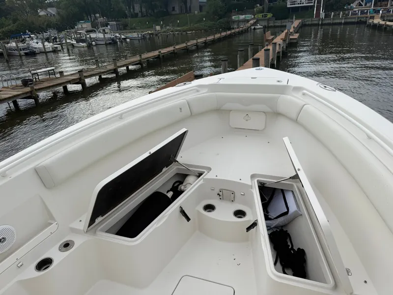 Slide: The Image of The image shows the bow of a 2014 Sailfish 290 CC boat with open storage compartments. - 13