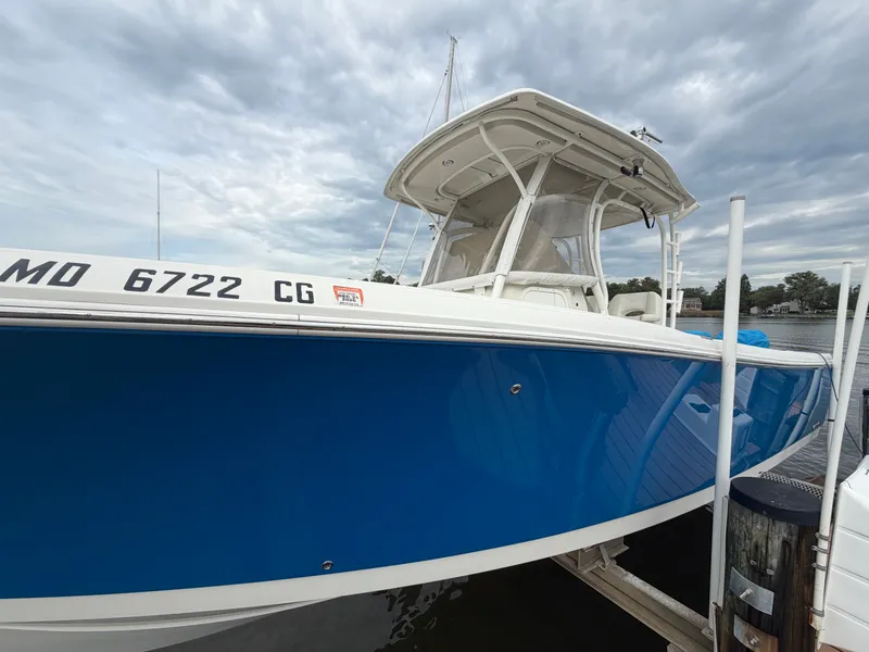 Slide: The Image of A blue 2014 Sailfish 290 CC boat docked under a cloudy sky. - 6