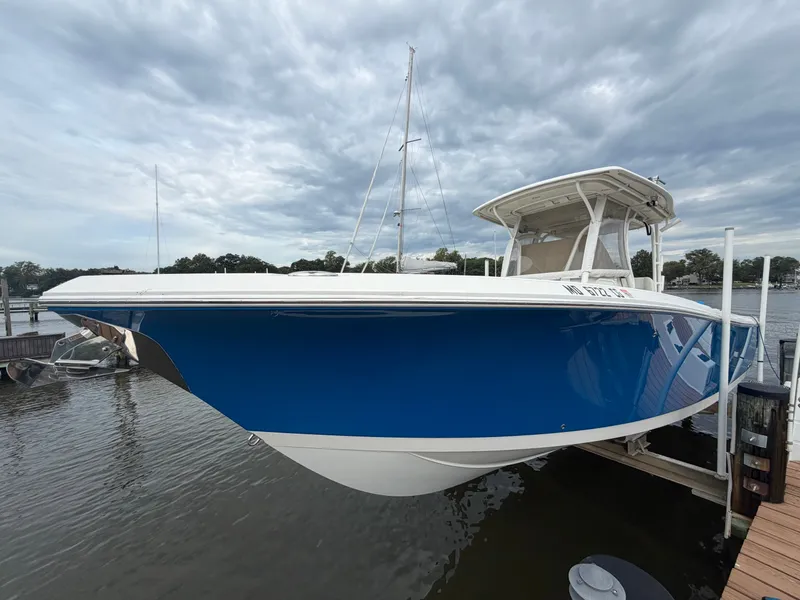 Slide: The Image of A blue and white 2014 Sailfish 290 CC is docked under a cloudy sky. - 5