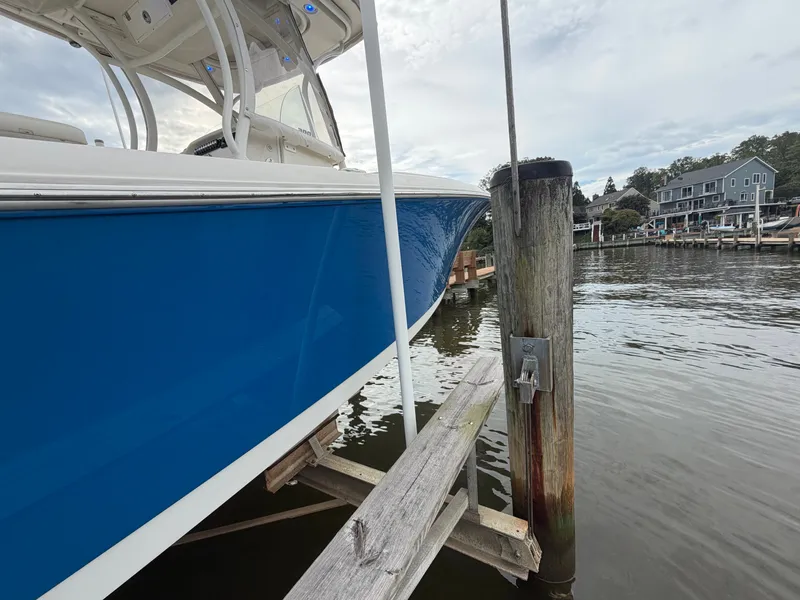 Slide: The Image of A blue boat docked at a wooden pier in a calm harbor. - 31