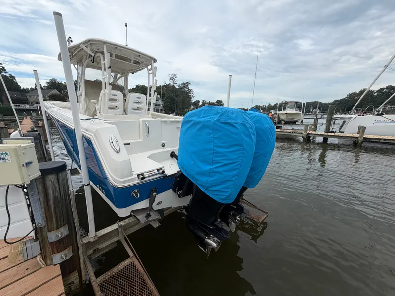 Slide: The Image of A 2014 Sailfish 290 CC with blue engine covers docked at a wooden pier. - 1