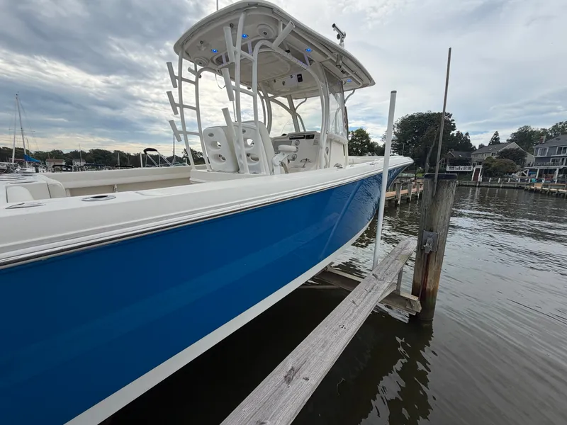Slide: The Image of A blue and white 2014 Sailfish 290 CC is docked. The sky is cloudy. - 29