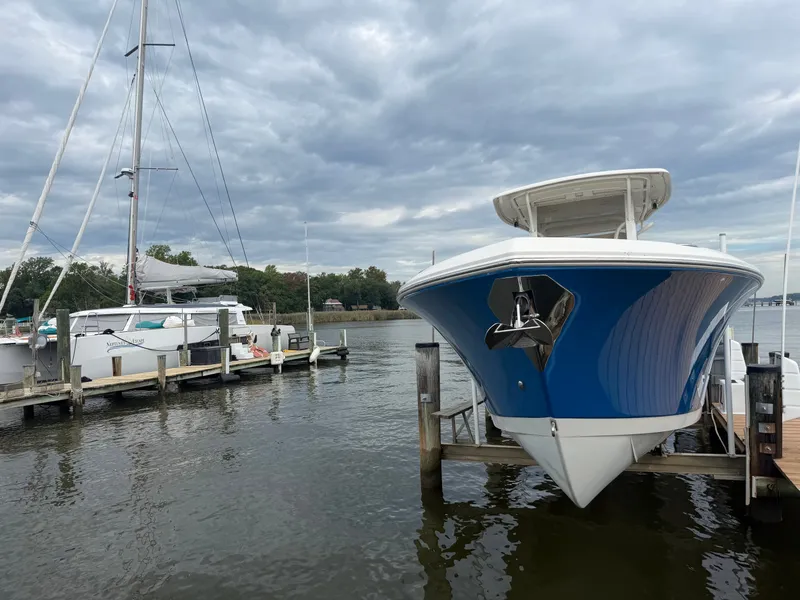 Slide: The Image of A blue and white 2014 Sailfish 290 CC is docked under a cloudy sky. - 3