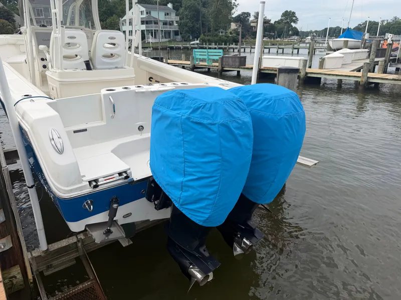 Slide: The Image of A 2014 Sailfish 290 CC with twin outboard motors covered in blue, docked by the water. - 34