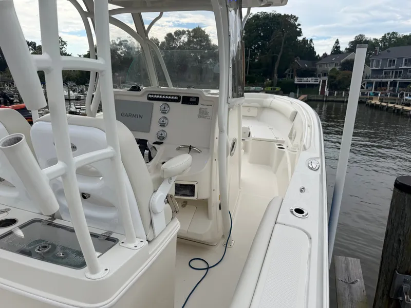 Slide: The Image of A 2014 Sailfish 290 CC with white interior and Garmin navigation, docked at a calm harbor. - 28