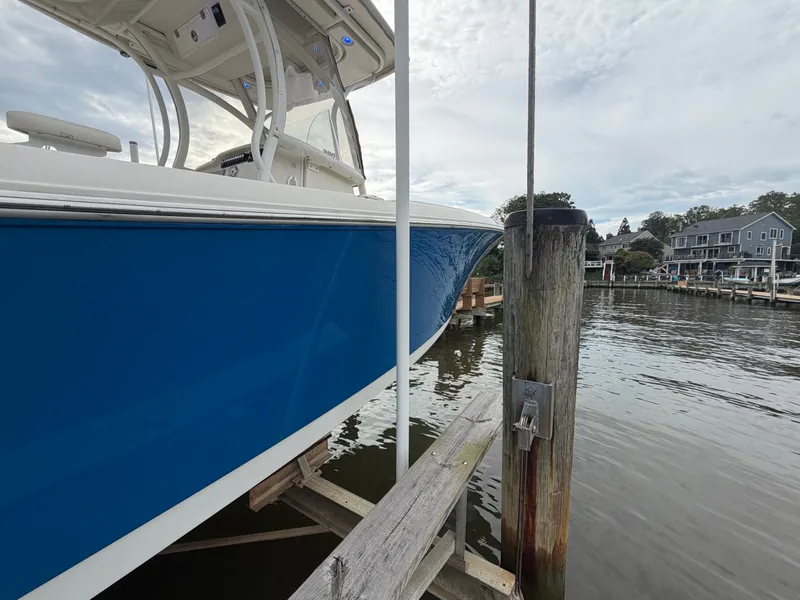 Slide: The Image of A blue boat docked at a wooden pier in a calm harbor setting. - 32