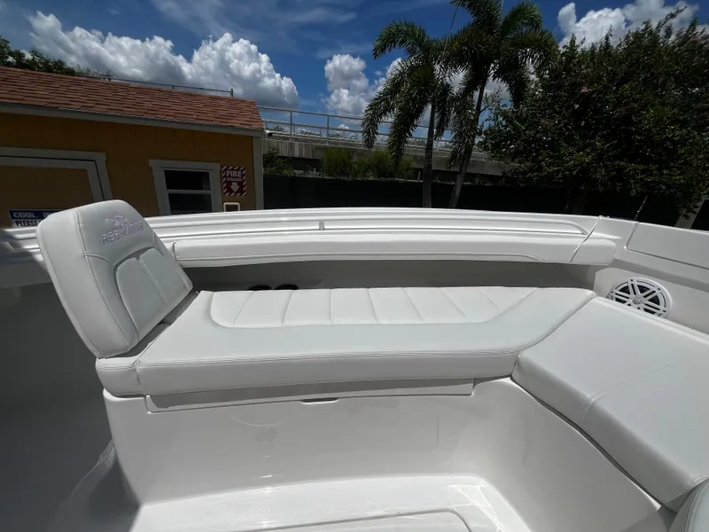 Slide: The Image of 2025 Regulator 23 boat with white cushioned seating and palm trees in the background. - 21
