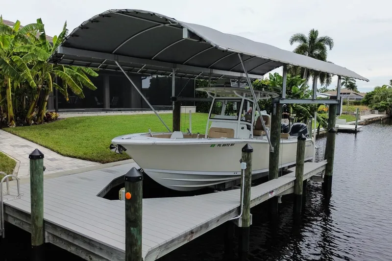 Slide: The Image of 2018 Sportsman Open 282 Center Console boat docked under a canopy by a waterfront. - 1