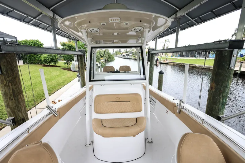 Slide: The Image of 2018 Sportsman Open 282 Center Console boat docked by a canal, featuring tan seating. - 16