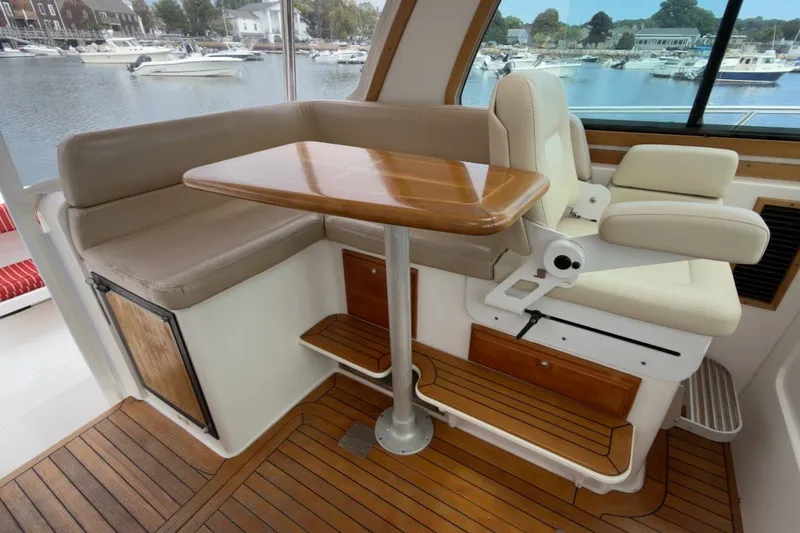 Slide: The Image of 2007 Sabre 34 Express boat interior with wooden table and seating by the harbor. - 13