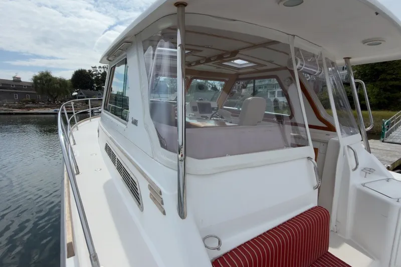 Slide: The Image of 2007 Sabre 34 Express yacht with enclosed cockpit and striped seating, docked by the water. - 25