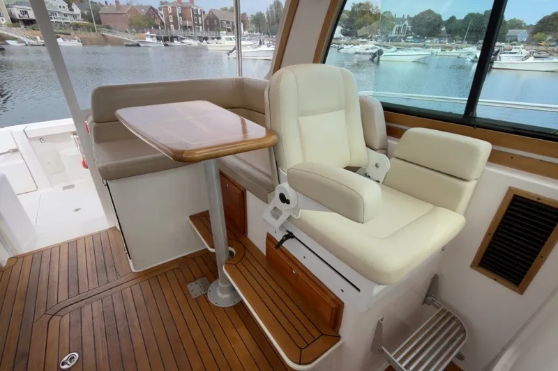 Slide: The Image of 2007 Sabre 34 Express interior with cream seating, wooden table, and scenic marina view. - 15
