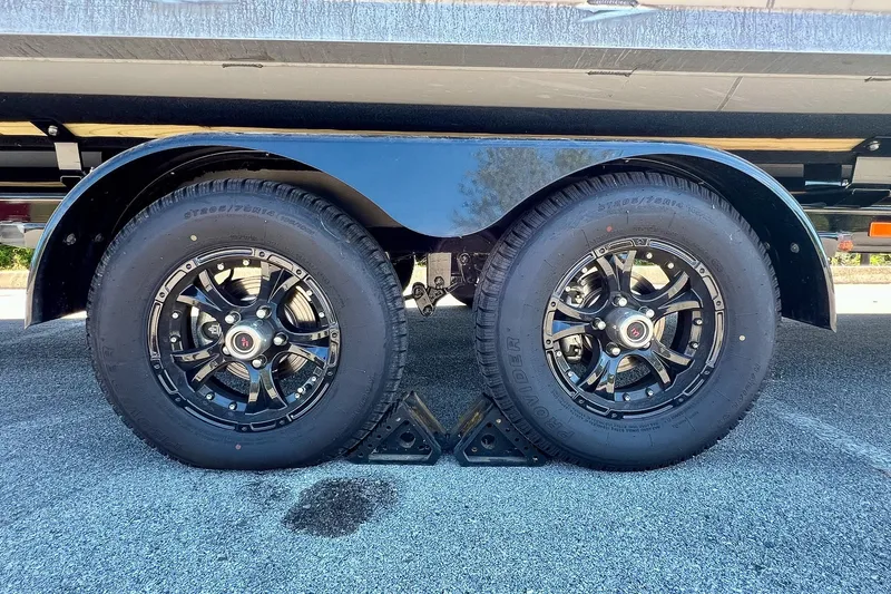 Slide: The Image of 2025 Harris Solstice 230 trailer wheels on asphalt, featuring black rims and sturdy tires. - 63