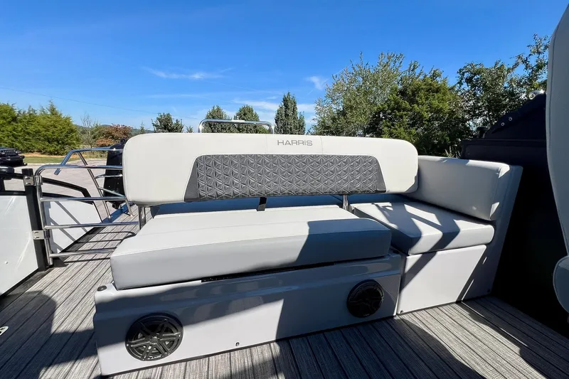 Slide: The Image of 2025 Harris Solstice 230 boat interior with cushioned seating and speaker, under clear blue sky. - 44