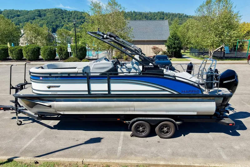 Slide: The Image of 2025 Harris Solstice 230 pontoon boat on trailer, parked outdoors with scenic background. - 10