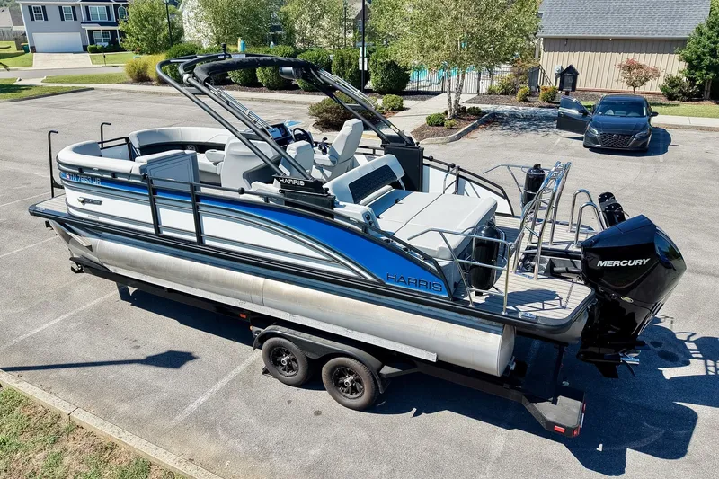 Slide: The Image of 2025 Harris Solstice 230 pontoon boat on trailer, parked in residential area. - 11