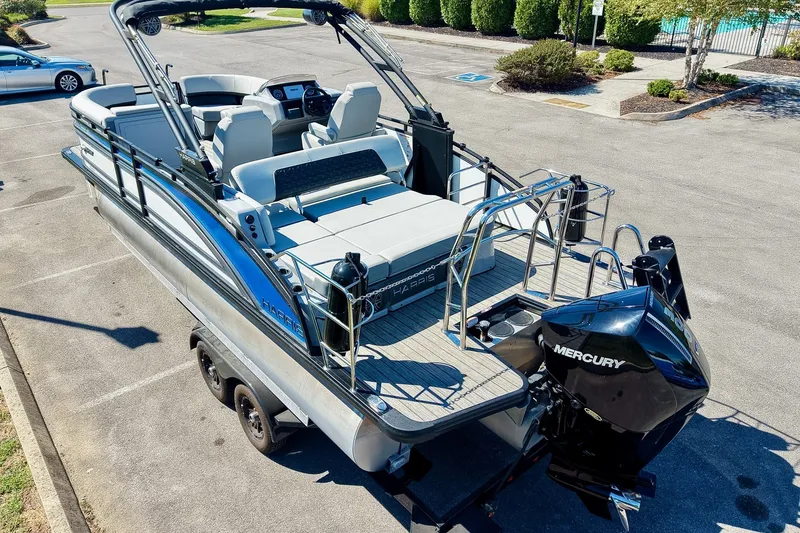 Slide: The Image of 2025 Harris Solstice 230 pontoon boat with Mercury engine, parked on a trailer. - 12