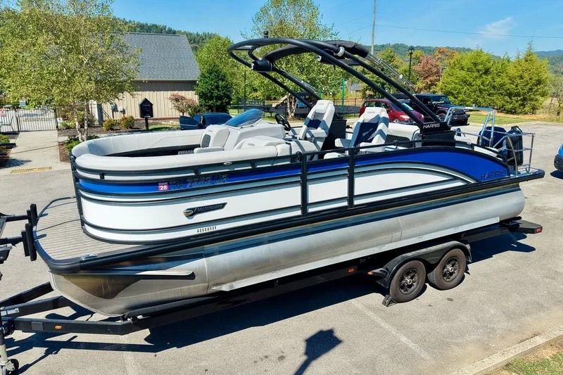 Slide: The Image of 2025 Harris Solstice 230 pontoon boat on trailer, parked outdoors in a scenic area. - 9