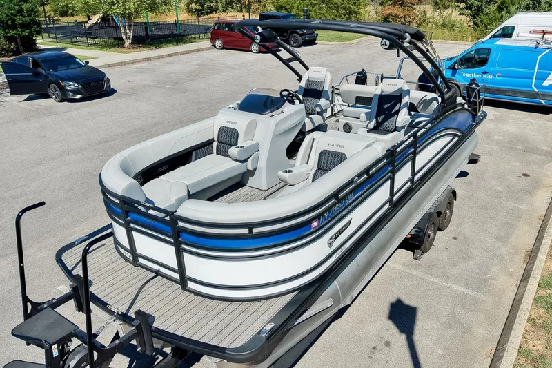 Slide: The Image of 2025 Harris Solstice 230 pontoon boat parked in a lot, showcasing sleek design and seating. - 8