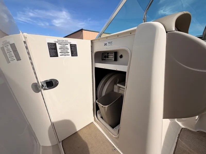 Slide: The Image of The image shows the interior of a 2006 Sea Ray 220 Sundeck boat. Visible are a storage area with a trash bin and control panel. - 37