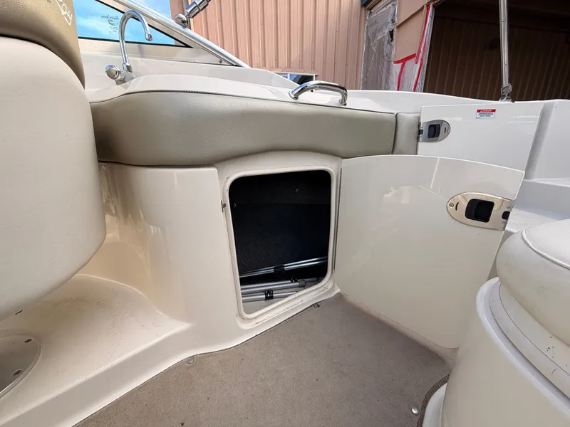Slide: The Image of Interior view of a 2006 Sea Ray 220 Sundeck with open storage compartment and beige upholstery. - 18